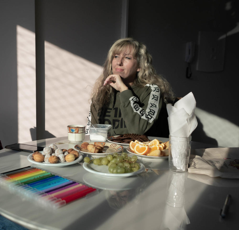 Laryssa Moskvichova and her children fled the war in Ukraine 3 months ago and resettled in Prudentópolis, a Brazilian town founded by Ukrainians. She's been baking and selling Ukrainian specialties in her new home — like the <em>oreshki </em>on the plate. It's a walnut-shaped cookie filled with <em>doce de leite. </em>The markers belong to her 6-year-old daughter, who had just been coloring.