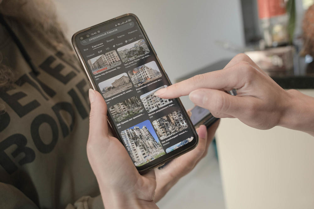 Anastasiia Ivanova shows images of her home city of Kharkiv on her phone, depicting the destruction during the Russian invasion that began on Feb. 24.