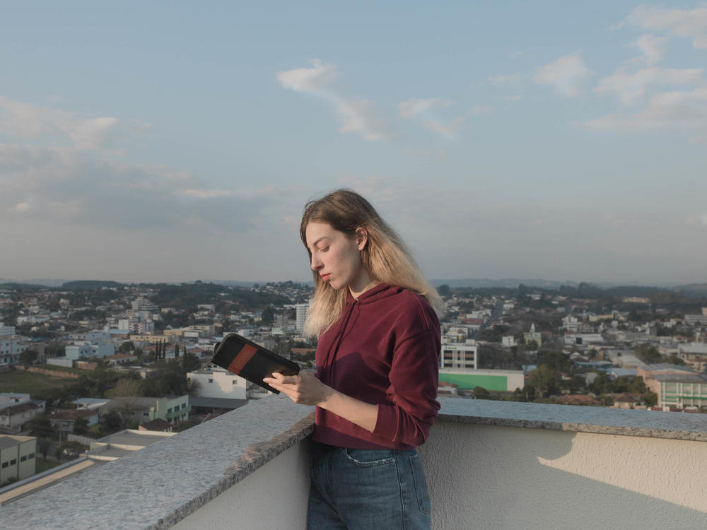 Ukrainian refugee Anastasiia Ivanova reads the Bible on the terrace of the apartment in Prudentópolis, Brazil, where she now lives with her mother and siblings. The devout 22-year-old says her faith is what's helped her get through all of her trials. She brought her Bible with her when the family fled Kharkiv.
