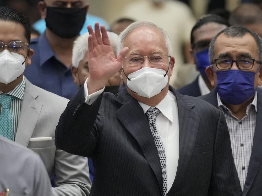 Former Malaysian Prime Minister Najib Razak, center, wearing a face mask, waves as he arrives at the Court of Appeal in Putrajaya, Malaysia, Tuesday, Aug. 23, 2022.