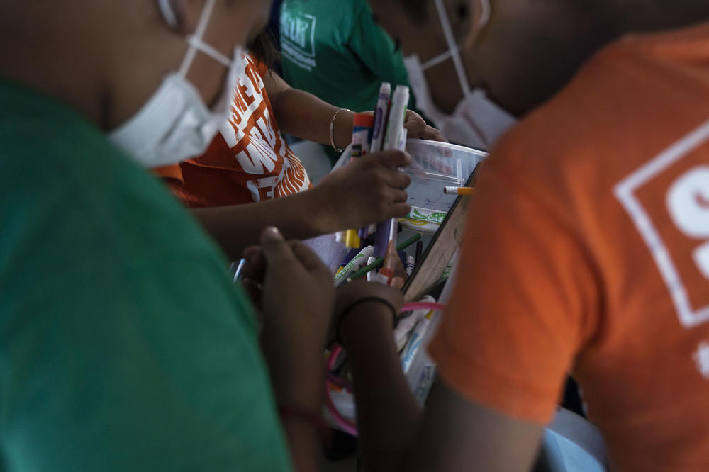 Children pick out drawing materials during class.