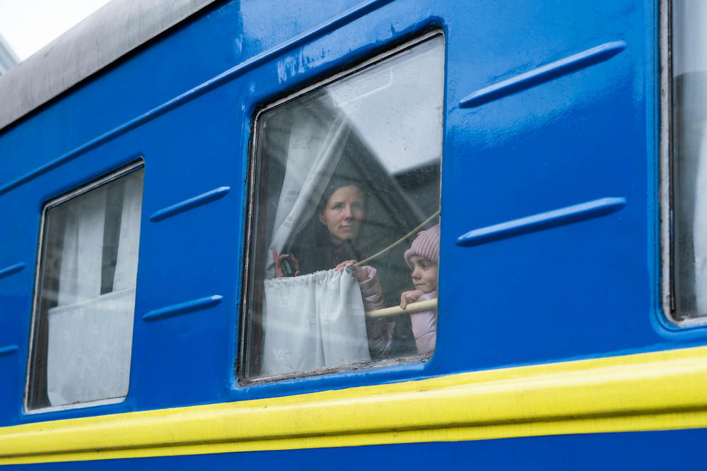 A woman and her daughter take a train out of Lviv toward Poland in March, leaving her husband behind on the platform.