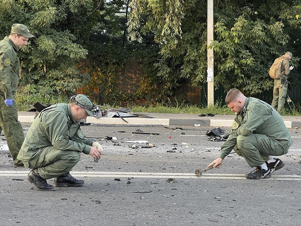 Investigators work on the site of explosion of a car driven by Daria Dugina outside Moscow.