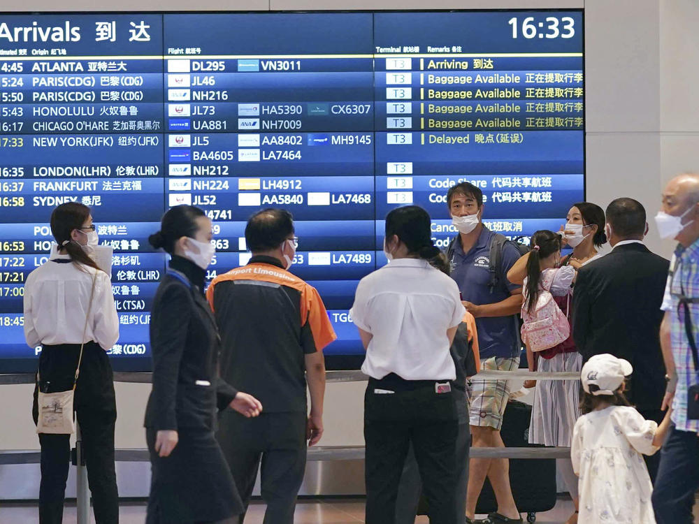 People wearing face masks are seen at an arrival lobby of Haneda airport in Tokyo on Aug. 23, 2022, amid the coronavirus pandemic.