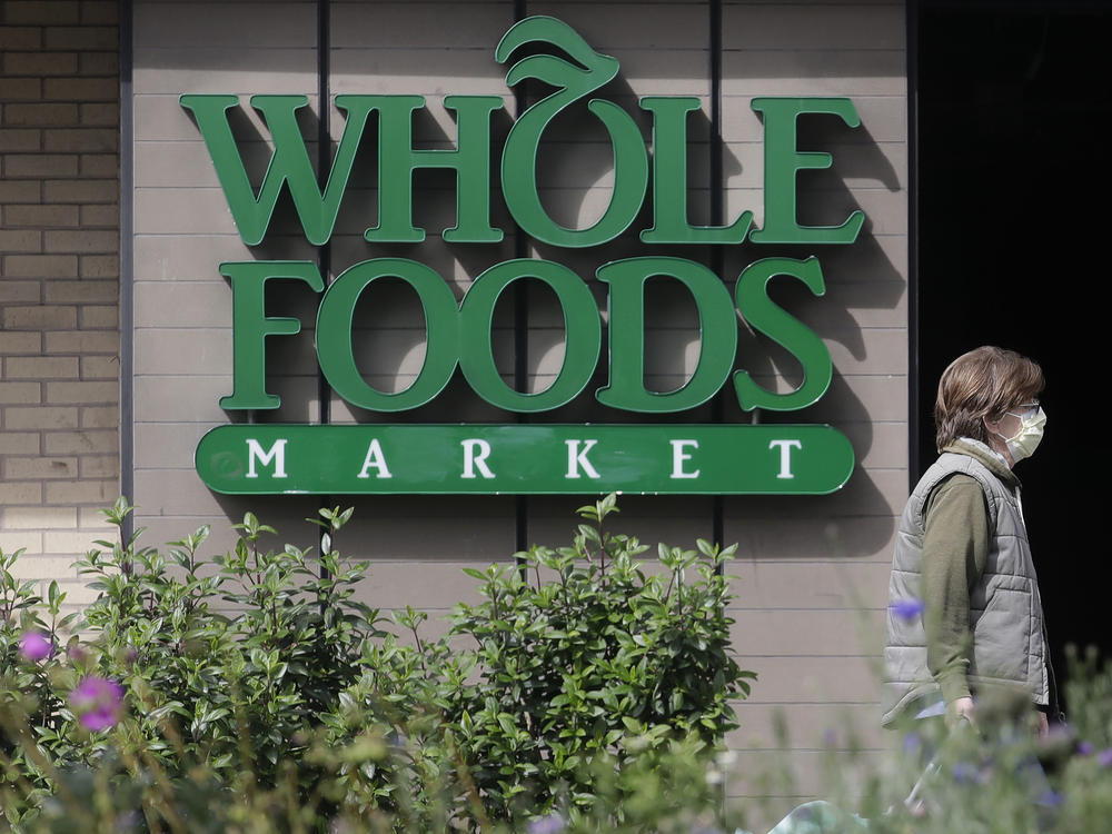 A pedestrian wears a mask while walking past a sign for a Whole Foods Market in San Francisco, Tuesday, March 31, 2020.