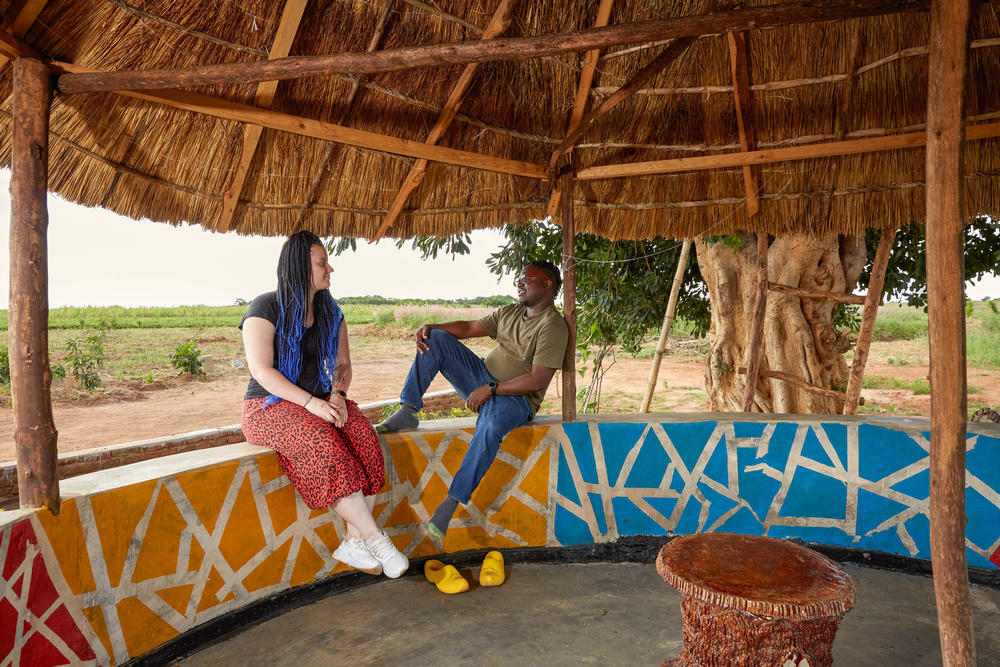 Fiona and Patrick sit on the wall of the outdoor dining area which forms the center of the couple's farm and compound in Malawi.