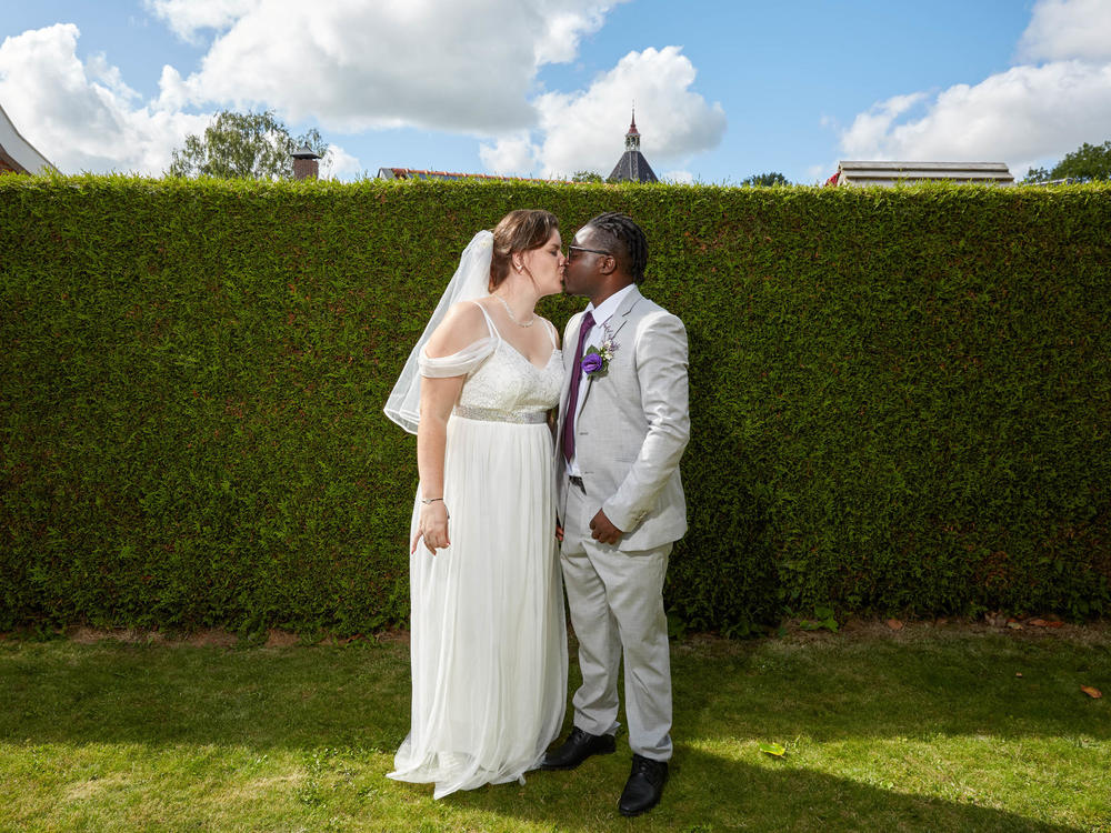 Fiona ten Have and Patrick Phiri pose for a wedding portrait in front of the same hedge where NPR photographed them during his first visit to the Netherlands (see photo, below).