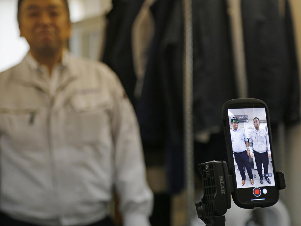 General Manager Tomohiko Kojima takes a TikTok video with CEO Daisuke Sakurai, as seen in the screen of the cell phone, at the Tokyo headquarters office of Daikyo Security Co. in Tokyo Monday, Aug. 22, 2022.