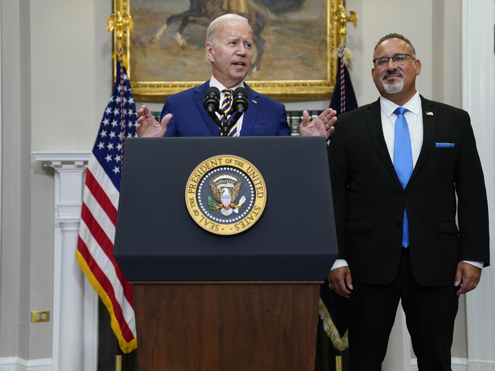 President Joe Biden speaks about student loan debt forgiveness in the Roosevelt Room of the White House on Wednesday as Education Secretary Miguel Cardona listens at right.