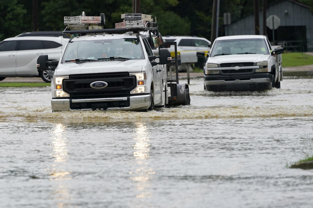 A couple of pickup trucks creep through floodwaters in Richland, Miss., following a morning of torrential rains, Wednesday, Aug. 24, 2022.