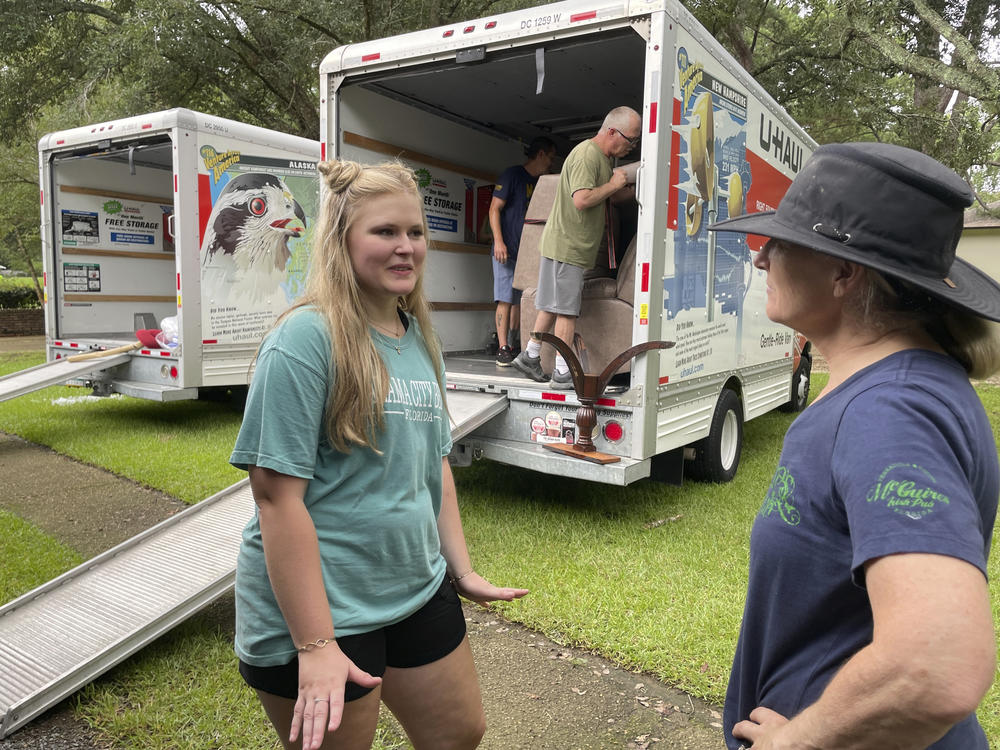 Medical student Emily Davis, left, speaks with her landlord Suzannah Thames on Friday as workers move furniture, appliances and other belongings out of a home Davis and her husband are renting in a flood-prone area of Jackson, Miss.