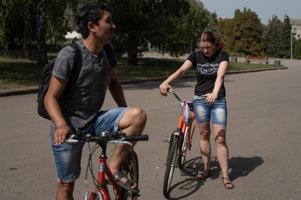 Oleksander Olaiarov (left) rides his bicycle with Oksana Morgun through the center of Slovyansk.