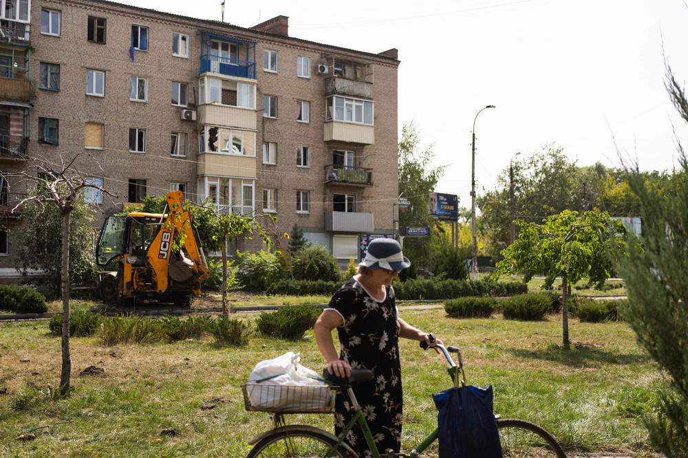 Viktoria Batychenko walks her bike in central Slovyansk where missiles hit in the morning on Sunday.