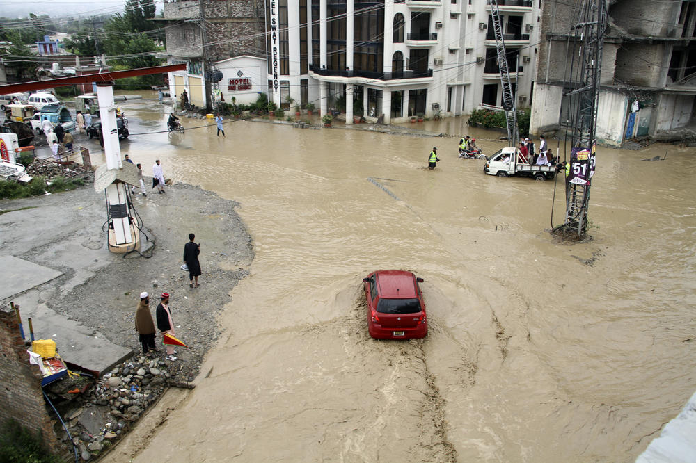 Pedestrians and vehicles navigate flooded roads after heavy monsoon rains in Mingora, in the Swat Valley, on Aug. 27.