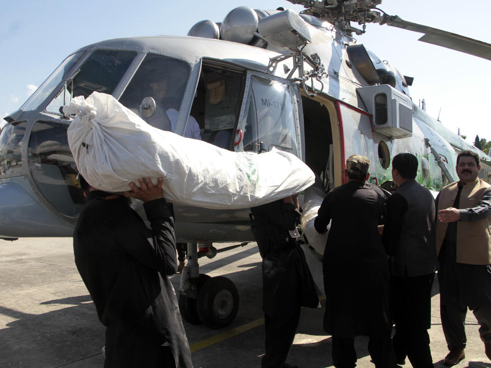 Tents for flood-affected people are loaded to a helicopter by frontier constabularies, in Swat valley, Pakistan, Sunday, Aug. 28, 2022.