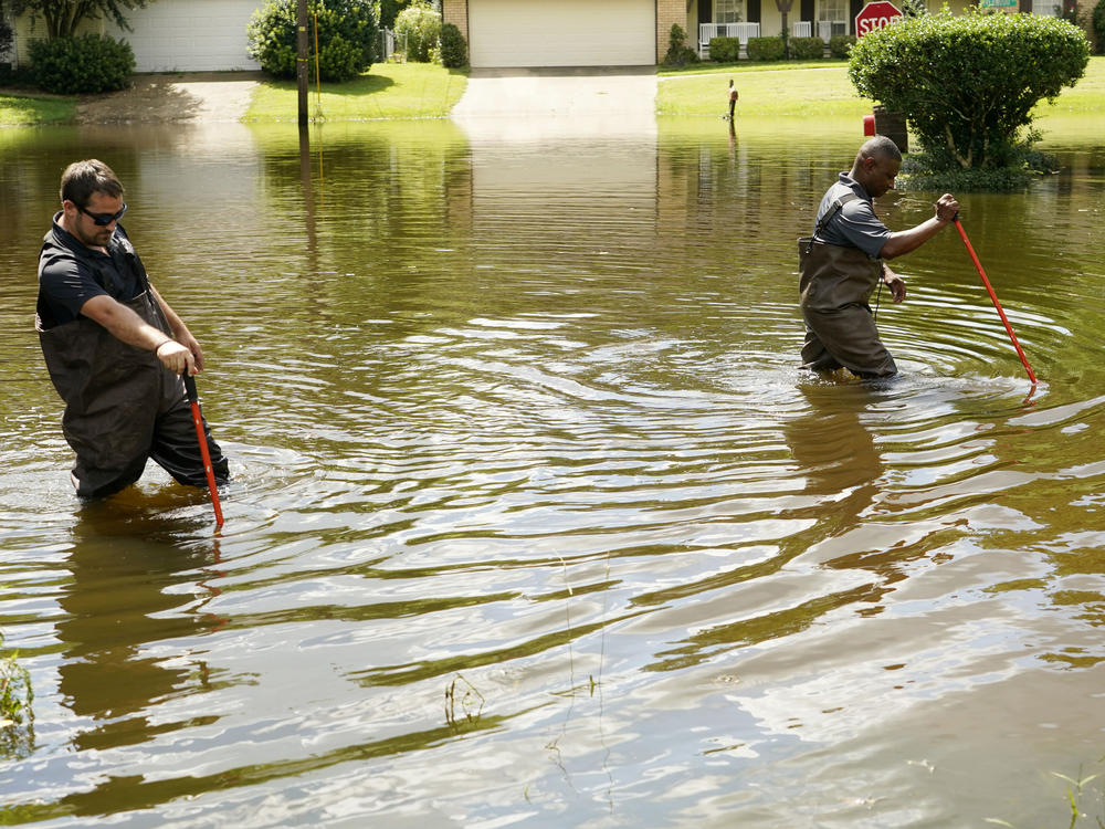 Hinds County Emergency Management Operations deputy director Tracy Funches, right, and operations coordinator Luke Chennault, wade through flood waters in northeast Jackson, Miss., Monday, Aug. 29, 2022.