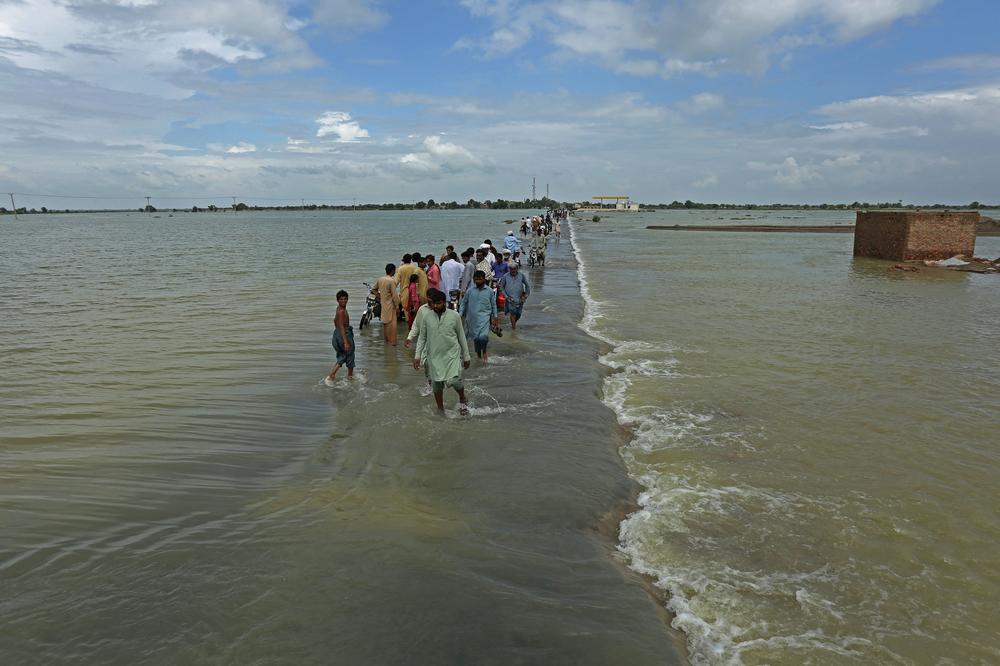 Stranded people wade through a flooded area after heavy monsoon rainfall in Rajanpur district of Punjab province on Aug. 25.