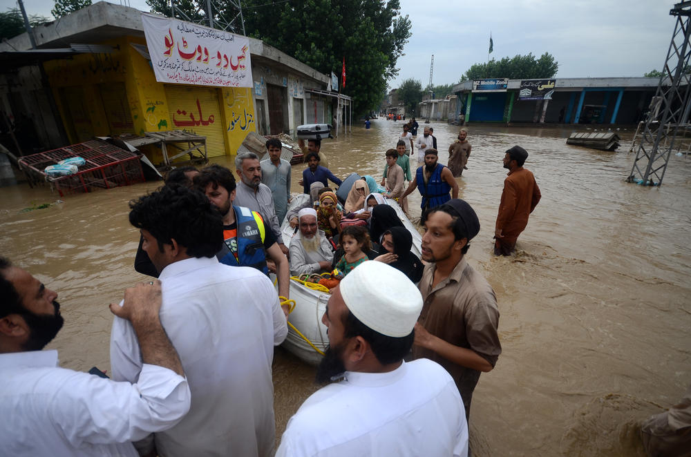 Displaced people wade through a flooded area in the city of Peshawar on Aug. 27.