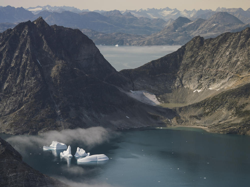 Icebergs are seen through a window of an airplane carrying NASA scientists as they fly on a mission to track melting ice in eastern Greenland on Aug. 14, 2019.