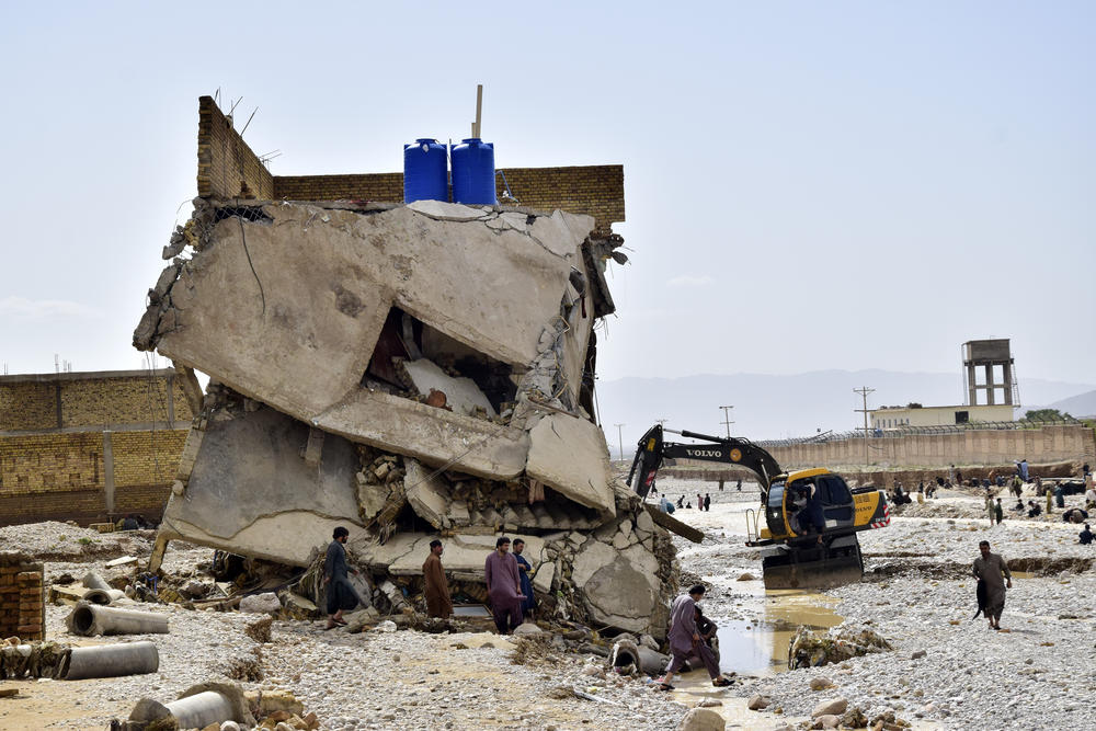 People stand by homes damaged by flooding after heavy rains, on the outskirts of Quetta, Pakistan, Aug. 27. Pakistani authorities say some 33 million people have been affected by this year's catastrophic floods.