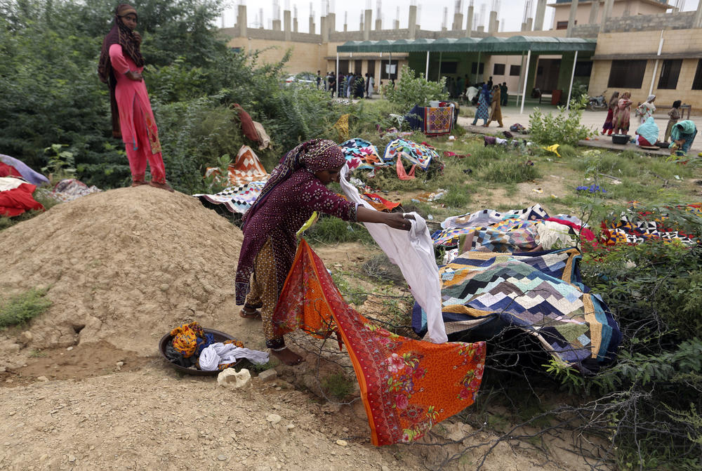 Pakistani women wash clothes on the grounds of a government college building after fleeing their flood-hit homes, in Karachi, Aug. 29. International aid was reaching Pakistan on Monday, as the military and volunteers desperately tried to evacuate many thousands stranded by widespread flooding.