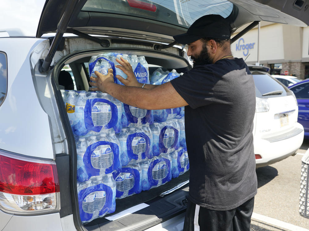 Rajwinder Singh, a gas station/convenience store owner, pats into place the 15 cases of drinking water he purchased from a Kroger grocery store into his vehicle, on Tuesday in Jackson, Miss.