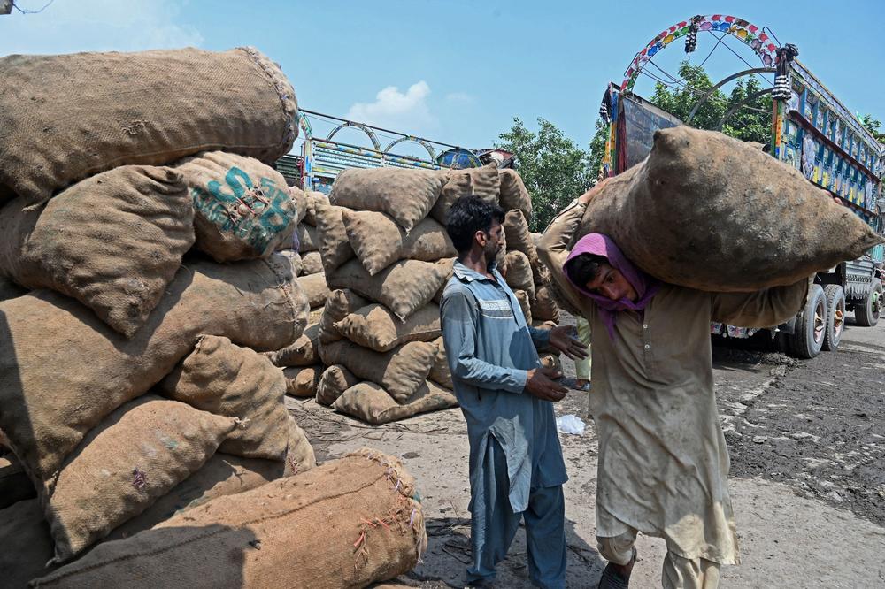 Laborers unload sacks of potatoes from a truck at a local market in Lahore on Aug. 30. Agricultural fields have been waterlogged due to catastrophic floods, leading to food shortages.