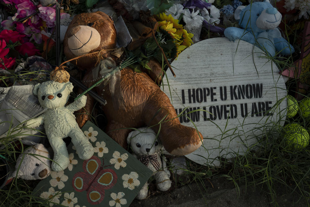 Plush toys and other objects are seen at a makeshift memorial for the victims of the mass shooting, three months after it happened.