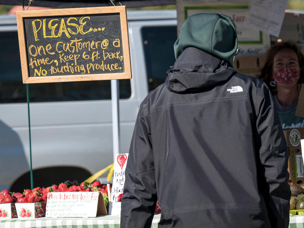 A sign tells shoppers to stand 6 feet back and not to touch the produce at a farmers market in San Rafael, Calif., in March 2020. Fearful of close-quarters in packed supermarkets that had empty shelves, many shoppers descended on farmers markets they rarely visited in the past.