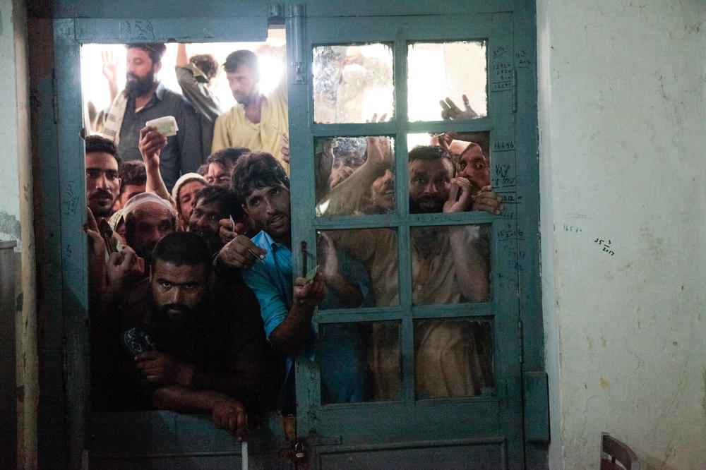 Flood refugees press against the door of the office where they can register for a camp offering tents as temporary housing.