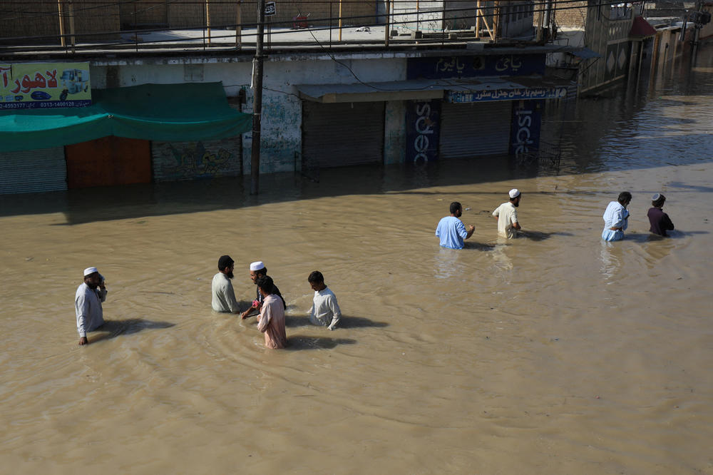 On Aug. 29, residents of Nowshera wade along a street flooded during the monsoon season.
