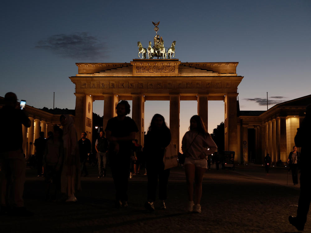 People walk near Berlin's Brandenburg Gate on the day a new law to save energy nationwide goes into effect on Thursday. The new law includes a wide variety of temporary measures, like banning the illumination of landmarks and regulating temperatures in public and private venues, to save electricity. These are a response to inflation and lower natural gas and other energy supplies from Russia.