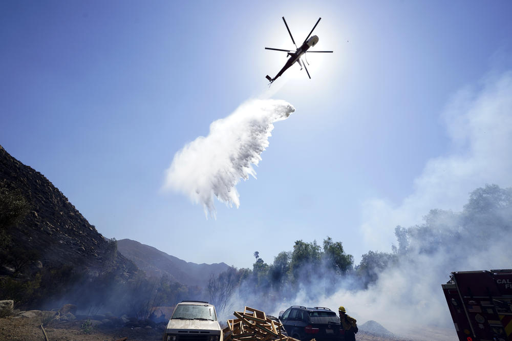 A helicopter drops water over a flareup alongside the Barrett Mobile Home and RV Park while fighting the Border Fire, Thursday, Sept. 1, 2022, in Dulzura, Calif. California wildfires chewed through rural areas north of Los Angeles and east of San Diego on Thursday.