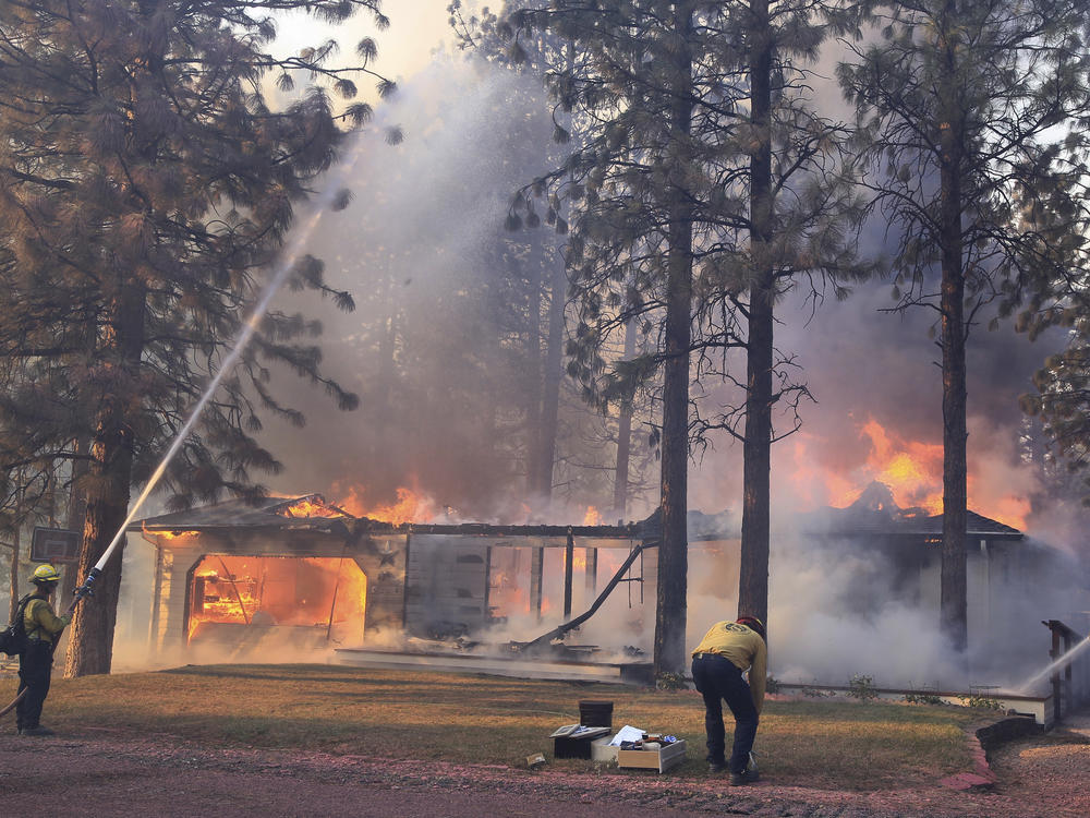 California Department of Forestry and Fire Protection firefighters try to stop flames from the Mill Fire from spreading on a property in the Lake Shastina subdivision northwest of Weed, Calif. on Friday.