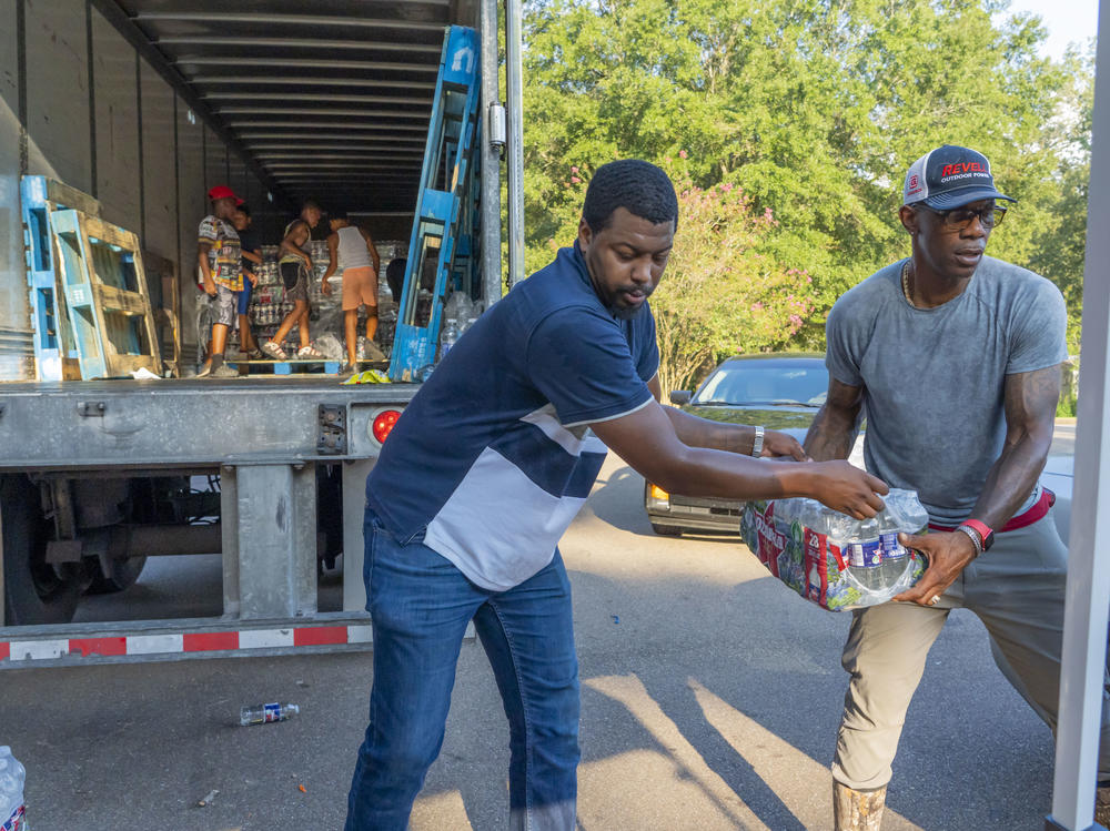 Jarvis Jones and John Knight help distribute free bottled water at the Sykes Park Community Center in Jackson, Mississippi.