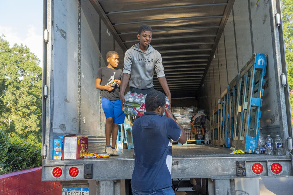 Tyisin Peoples, Joshua Freeman, and Jarvis Jones  help distribute free bottled water at the Sykes Park Community Center in Jackson, Mississippi.