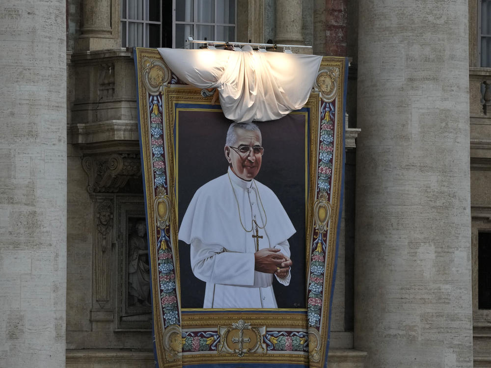 The tapestry depicting late Pope John Paul I hanging from the facade of St. Peter's Basilica, is unveiled during the beatification ceremony led by Pope Francis at the Vatican, Sunday, Sept. 4, 2022.