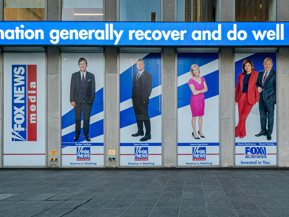 Among the stars being questioned under oath for Dominion Voting Systems' defamation suit against Fox News are Tucker Carlson, Sean Hannity and Maria Bartiromo. Banners bearing their images hang from Fox Corp. headquarters in New York City, first, second and fourth from left, respectively.