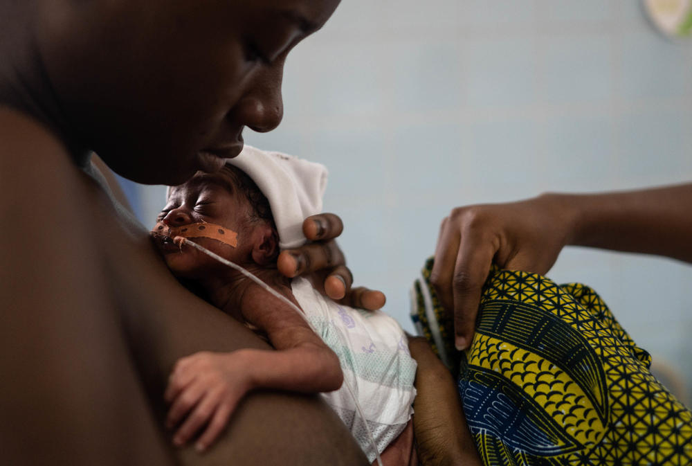Youal Emmnual, 15, holds her daughter, Lucy, as she is put into a kangaroo care carrier.