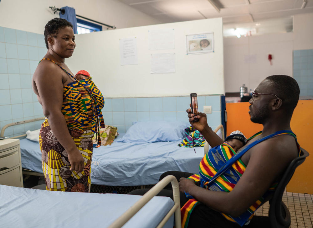 Ablodie Kouwasi gave birth to triplets. One of the babies died; the couple spends hours at a time holding the two surviving newborns in the hospital's kangaroo care ward. Dad Yappe Pako is multitasking, holding his son, Ambo Crisostome, while he takes a photo of his wife holding their daughter, Ambo Mari Este.
