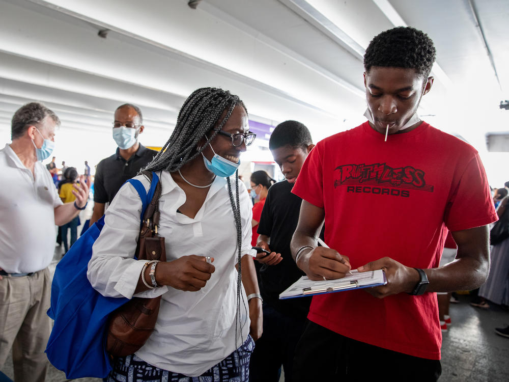 Layi Oniwinde, 16, fills out an election worker application as his mother, Adaobi Oniwinde, looks on with a smile in Wheaton, Md. 