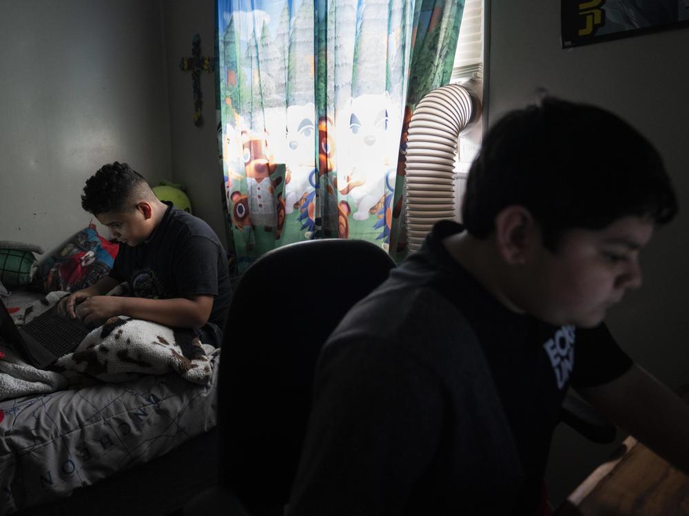Eloyd, 11, left, plays online video games with his brother Emmanuel, 12, right, at his home in Uvalde, Texas.