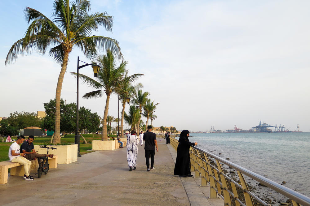 People stroll along a promenade along the shore of Jeddah.