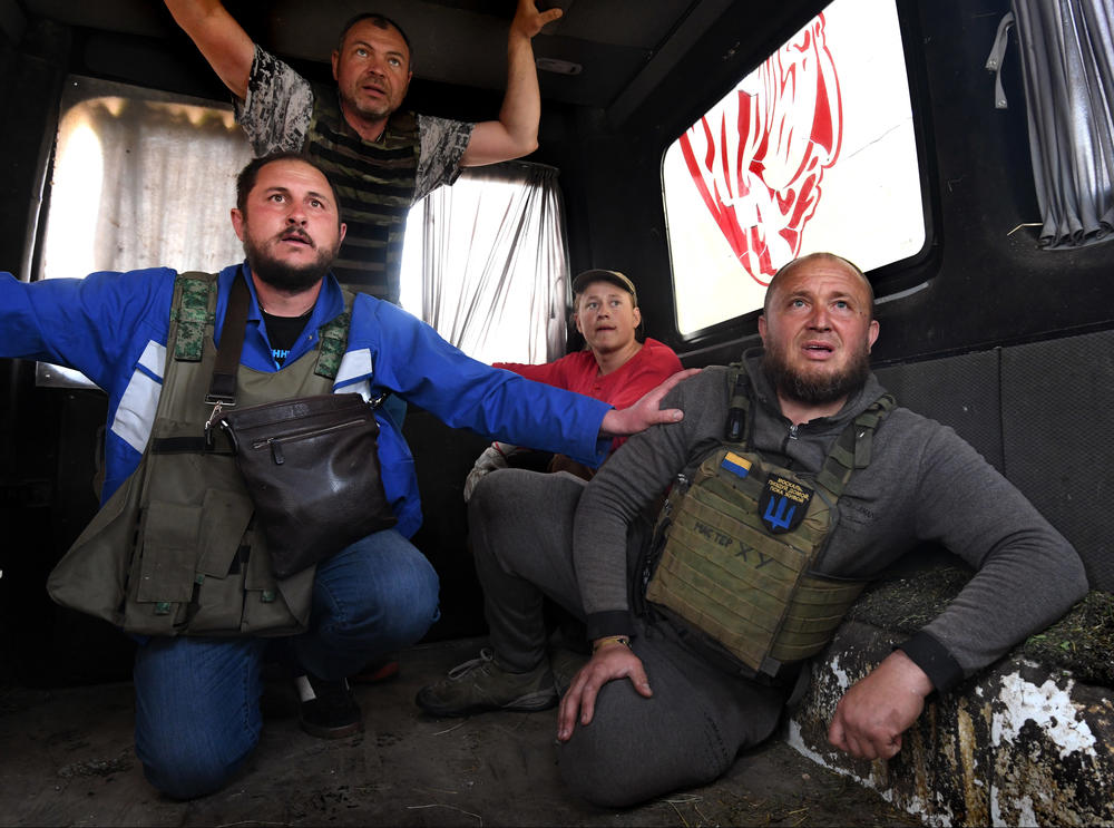 From left: Vitalii Ilchenko, Serhii Kolesnikov, Andrii Kharchenko and Oleksandr Kolomiiets rush away from Russian shelling that began while they were trying to rescue an ostrich from Feldman Ecopark on May 4.