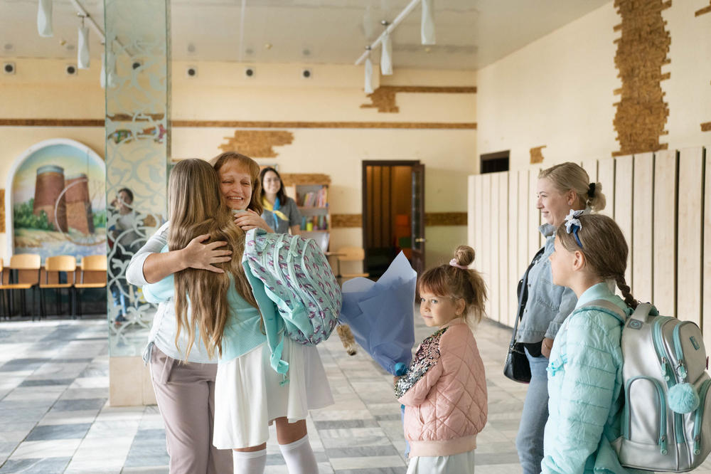 Students hug a teacher as they return to a private school in Dnipro.