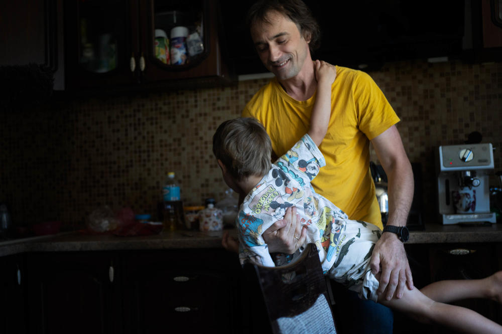 Serhii Sheremet holds his son Boris, 4, in the kitchen of their home in Dnipro.