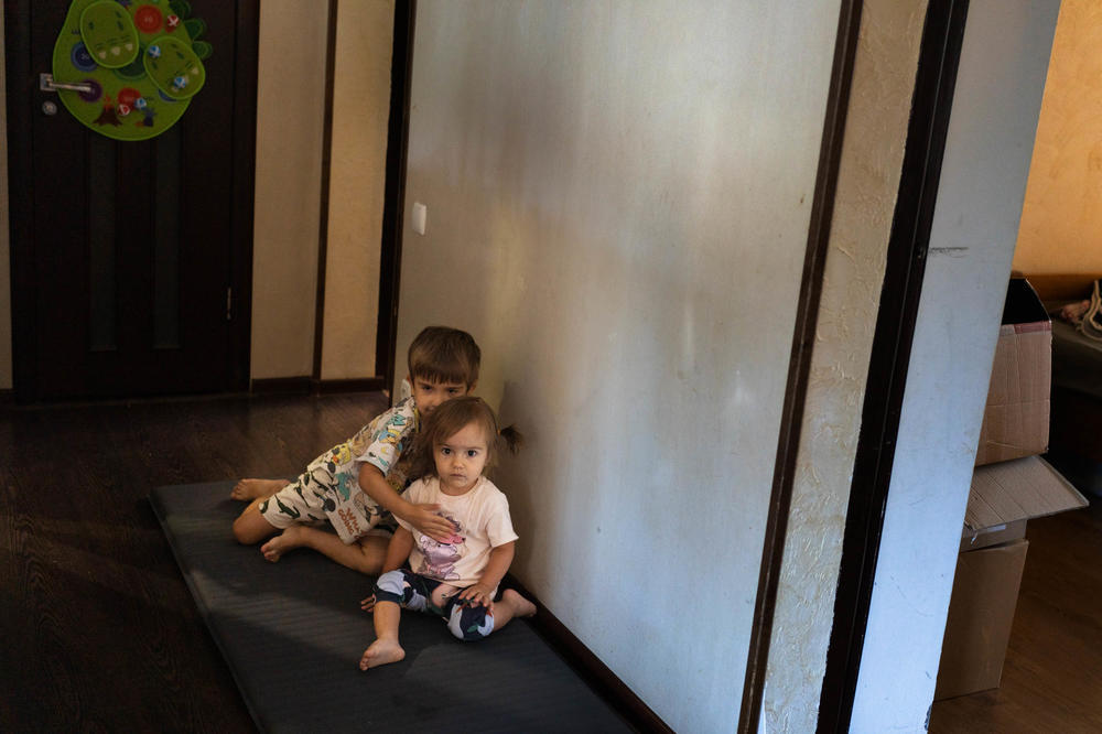Boris and his sister, Marina, stay between walls in a hallway in the center of their home while an air raid siren goes off.