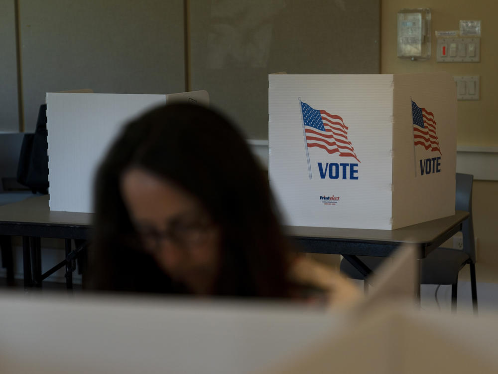 A voter in the foreground casts her ballot during the Republican primary election in Wilson, Wyo., on Aug. 16.