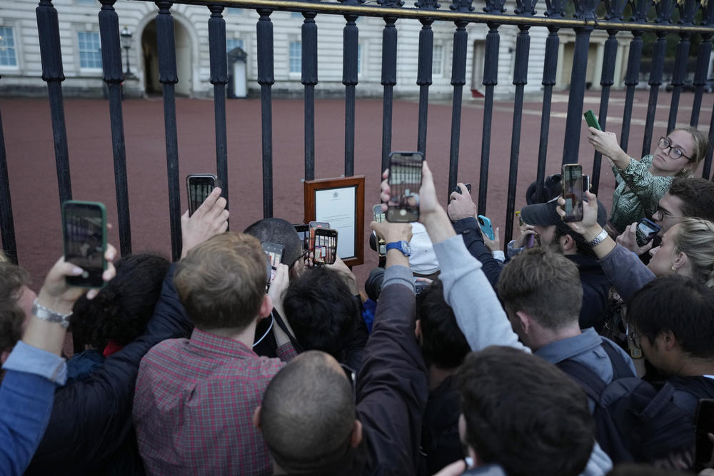 Crowds photograph an announcement of the death of Britain's Queen Elizabeth II as it is displayed on the gates of Buckingham Palace on Thursday. The statement reads: 