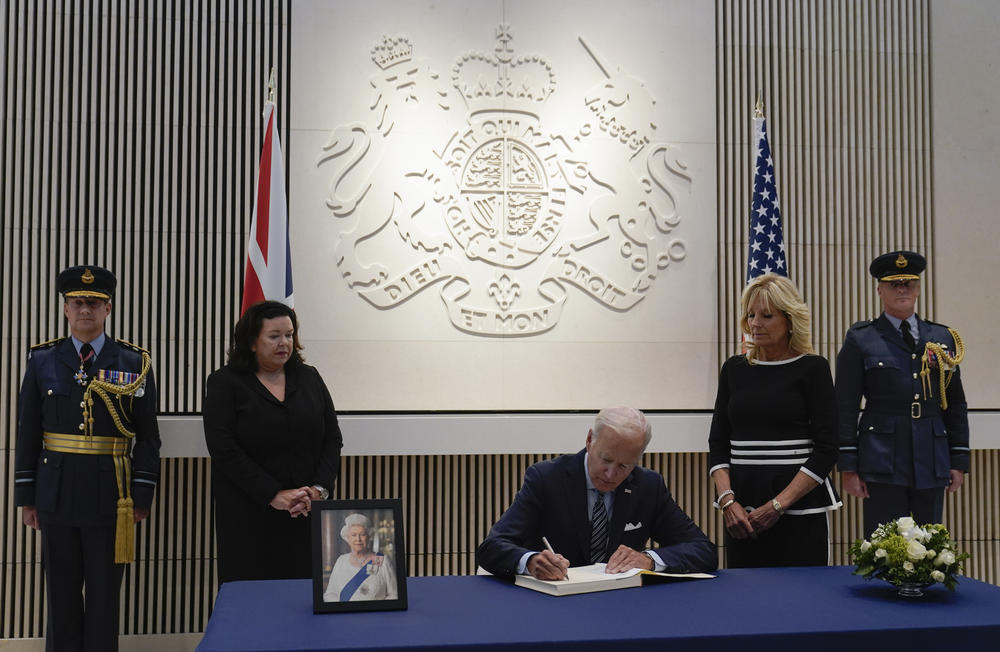 President Biden signs a condolence book for Queen Elizabeth II at the British Embassy in Washington on Thursday. First lady Jill Biden (second from right) and British Ambassador Karen Pierce (second from left) look on.